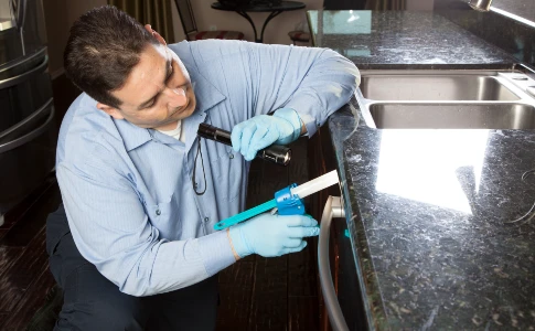 pest control tech baiting in kitchen
